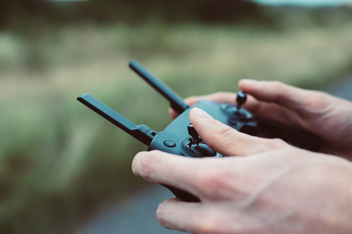 Mains tenant un contrôleur de drone avec boutons et manettes.