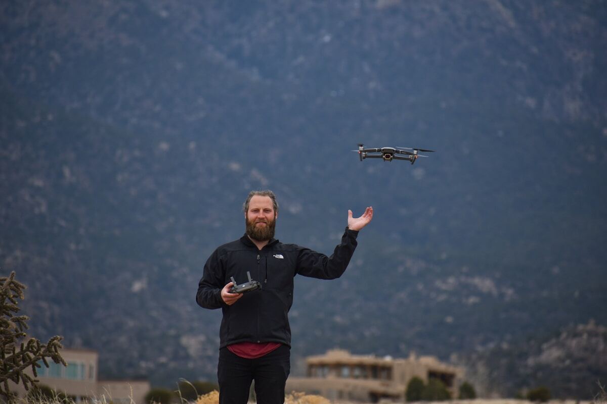 Homme barbu avec un drone volant au-dessus de lui.