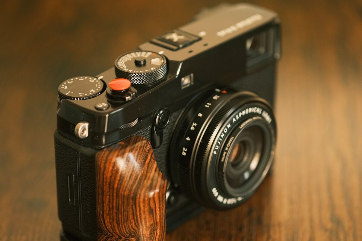 A black digital camera with a wooden grip.