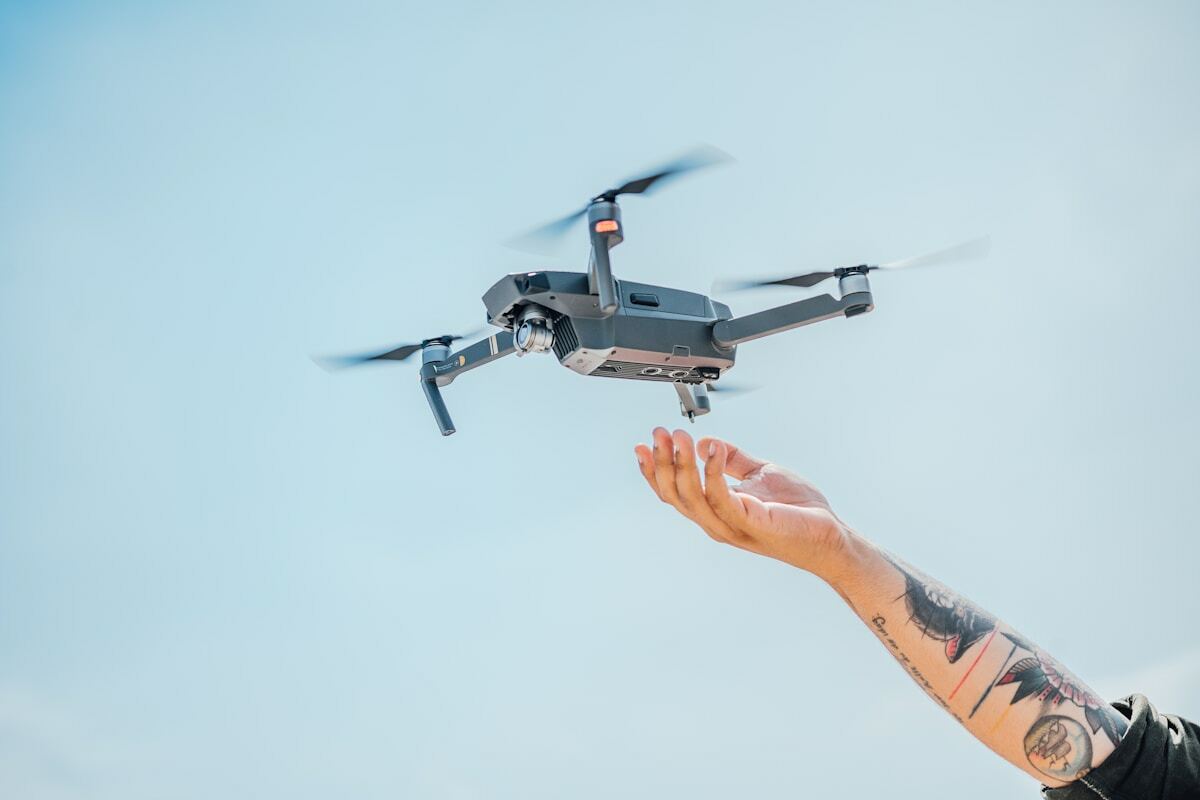 Drone volant près d'une main tatouée.