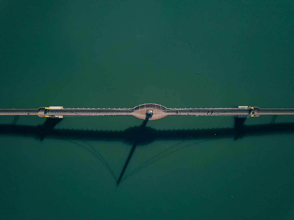 Pont suspendu enjambant un plan d'eau verdoyant.