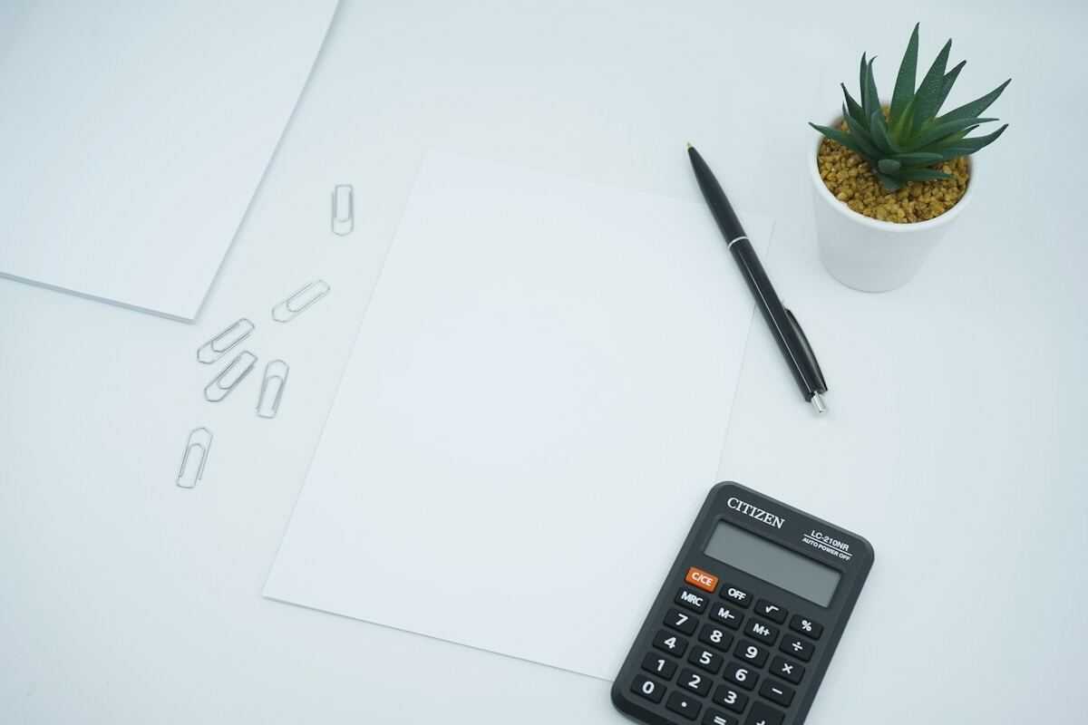 Bureau avec papier, crayon, calculatrice et plante succulente.