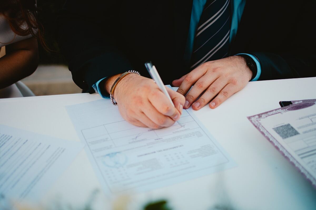 Mains d'un homme d'affaires signant un document officiel sur un bureau.