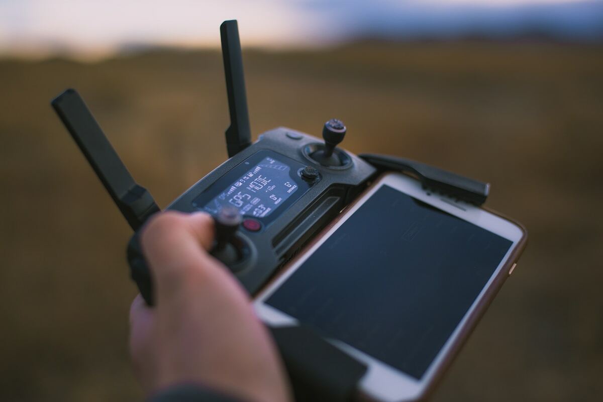 Contrôleur de drone avec écran tactile dans un paysage flou.