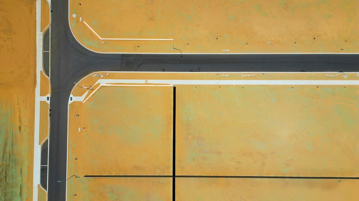 Intersection de routes avec marquages au sol et surface en béton ocre.