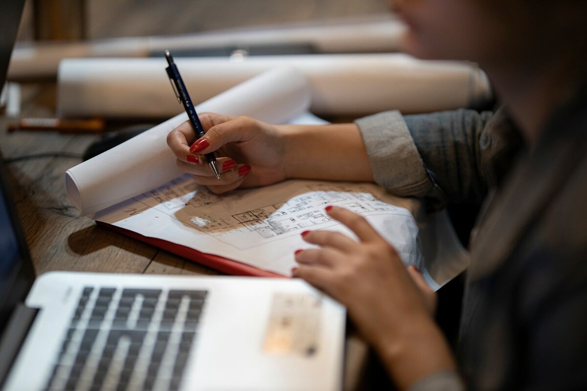 Personne écrivant dans un cahier avec un stylo à encre rouge.