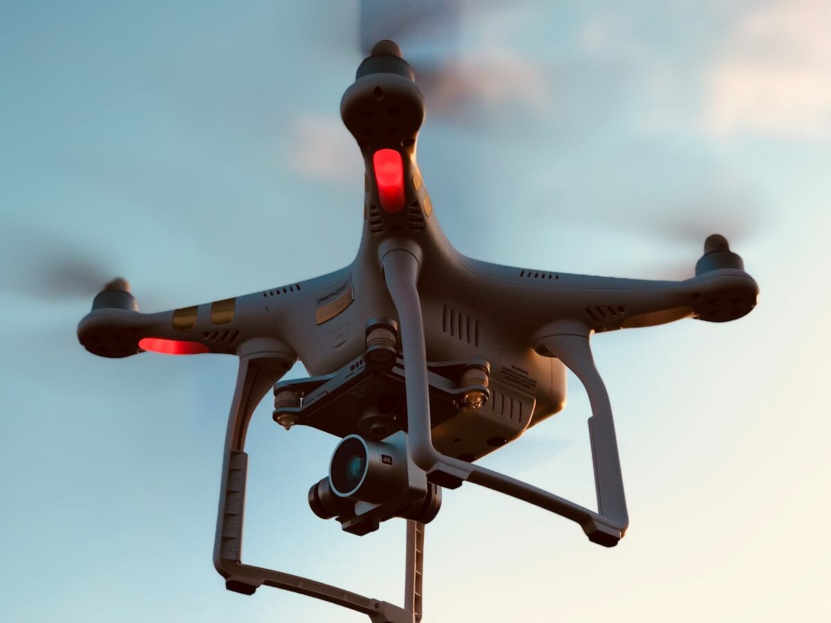 Drone volant avec caméra et lumières rouges.