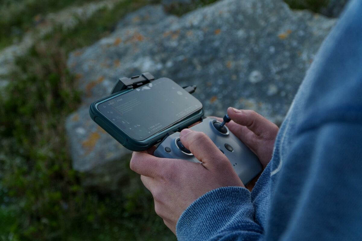 Personne jouant à un jeu vidéo portable dans un environnement naturel.